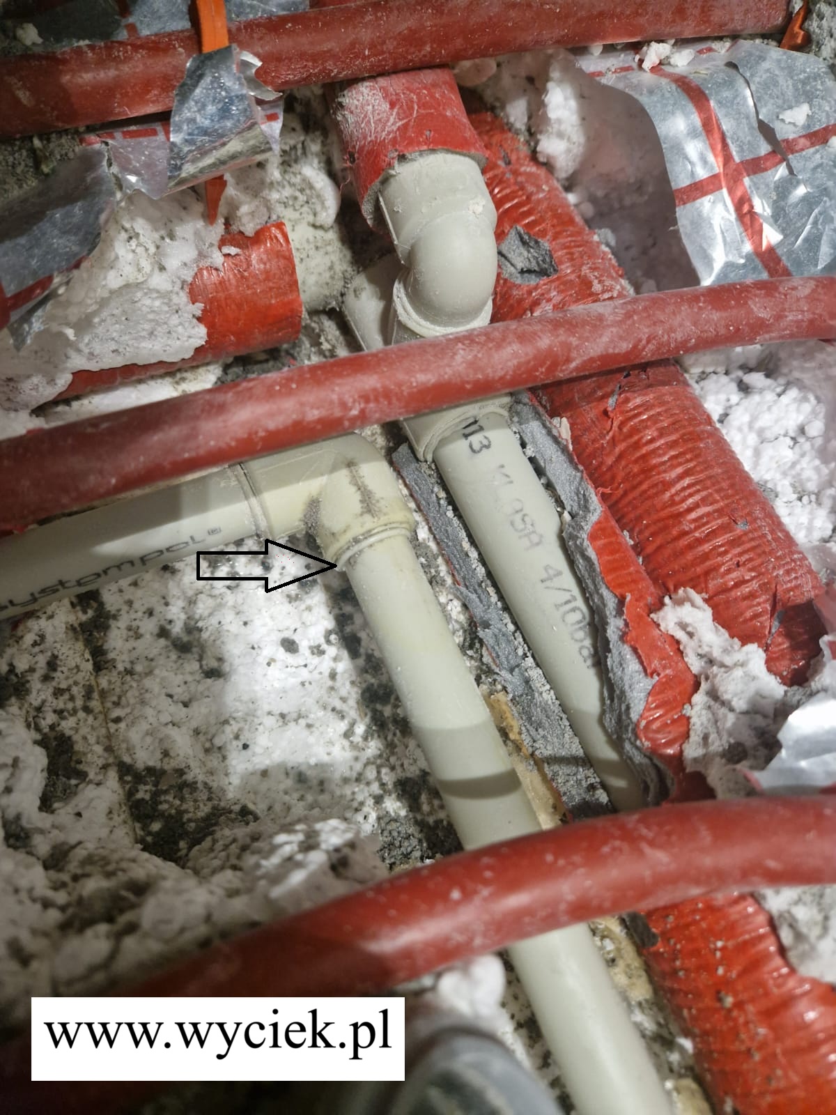 Miejsce wycieku wody na połączeniu rury PEX w instalacji podłogowej – widoczna nieszczelność