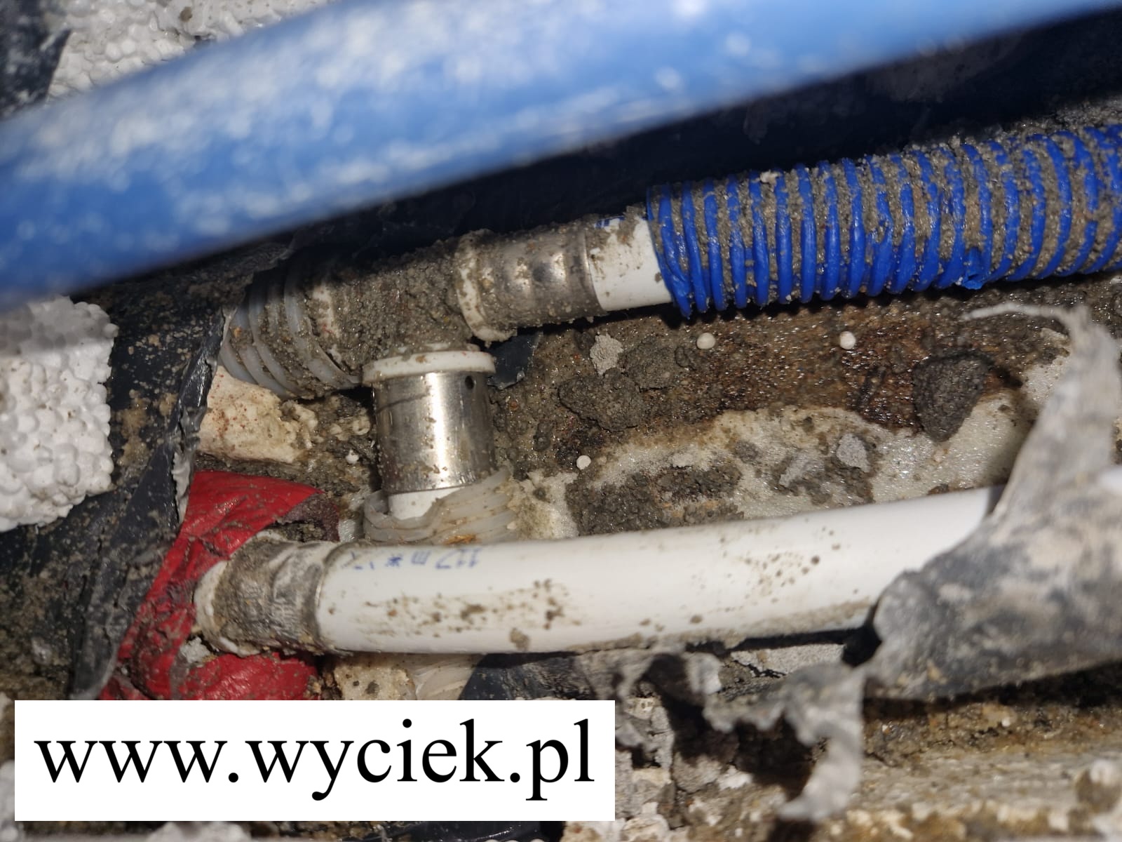 Brak zacisku rura PEX i niezaciśnięty trójnik pod podłogą powodujący wyciek wody